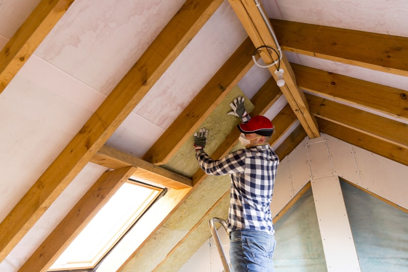 Man Installing Insulation In Attic