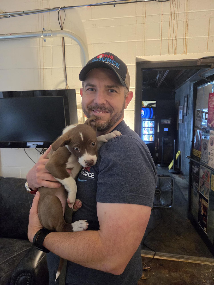 Chris from One Source holding Winston, his new brown and white puppy